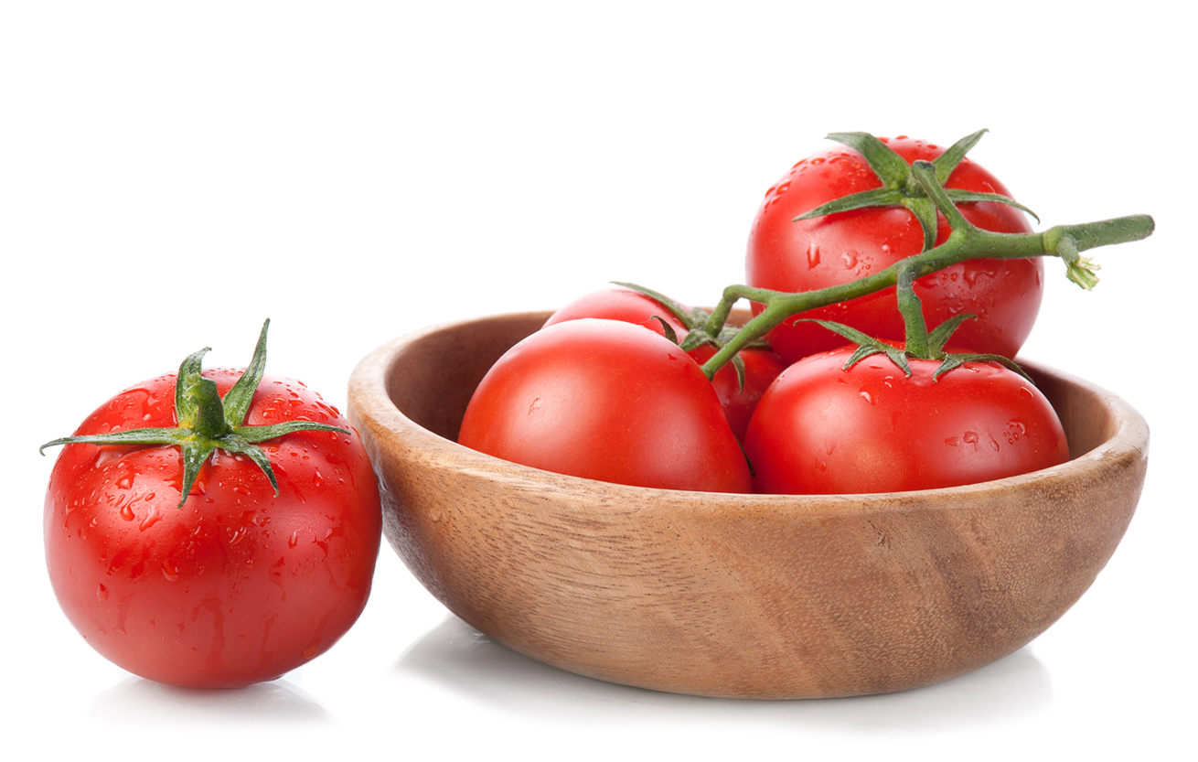 tomatoes in a wooden bowl isolated on white background