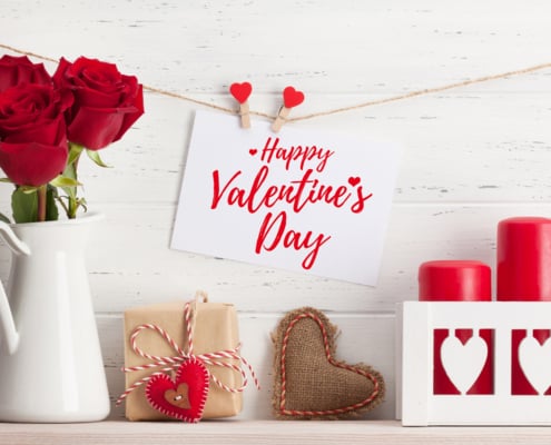 Valentines day greeting card with rose flowers and gift box on white wooden background