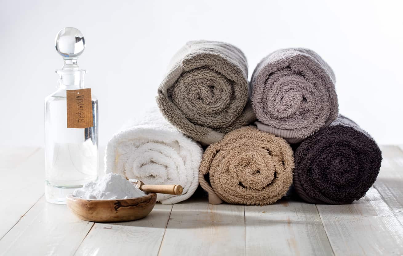 Green domestic housekeeping and sustainable cleaning laundry with chic homemade softener made of vinegar and baking soda for fluffy rolled towels on wooden background vinegar in laundry