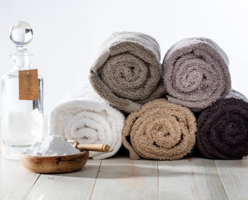 Green domestic housekeeping and sustainable cleaning laundry with chic homemade softener made of vinegar and baking soda for fluffy rolled towels on wooden background vinegar in laundry