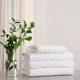 Fresh towels and green branches on light grey stone table in bathroom