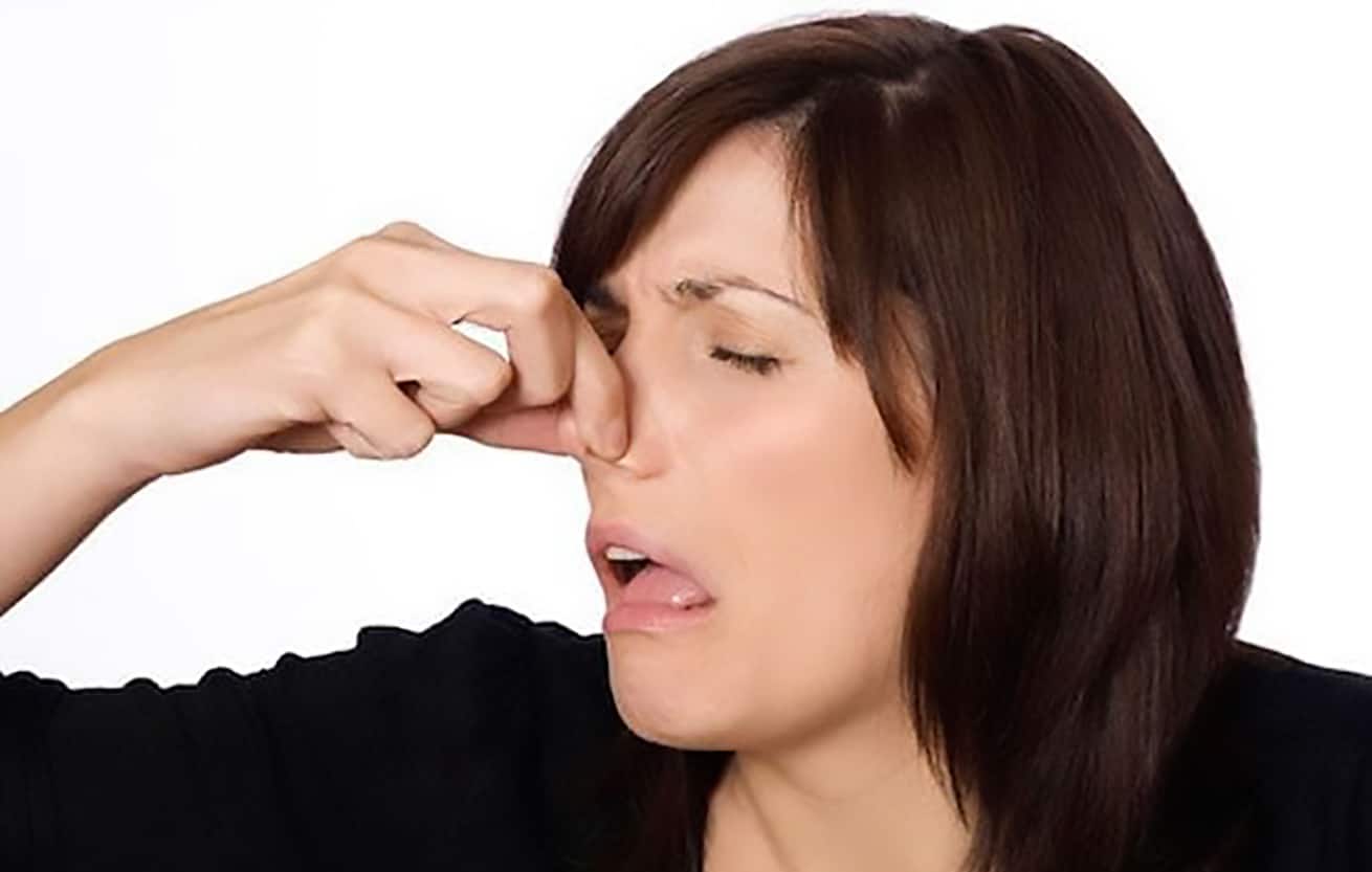 woman holding nose due to stinky smell