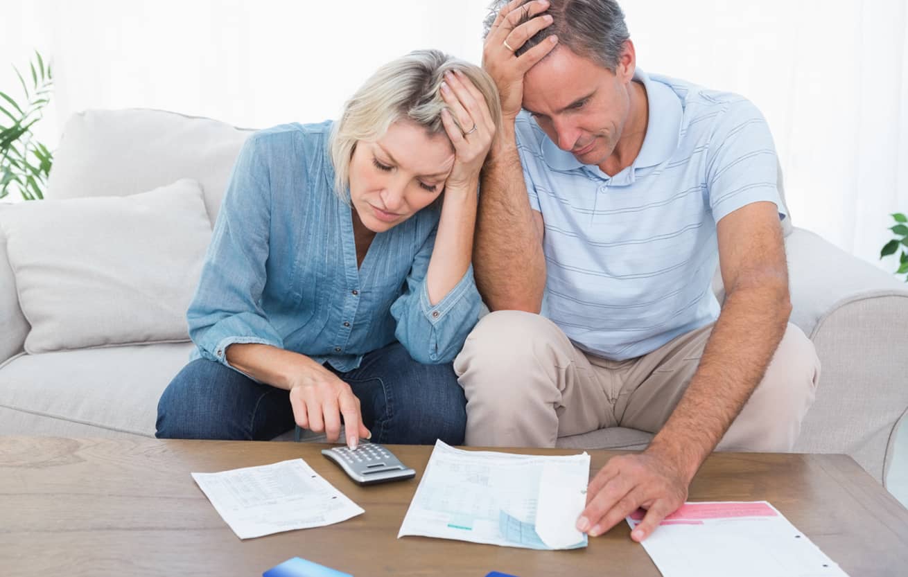 Worried couple going over finances at home in living room