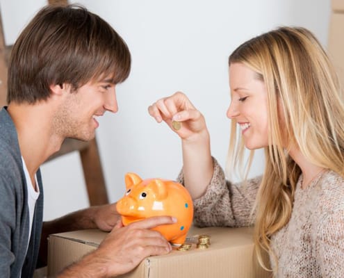 couple moving and thowing coins in a piggybank