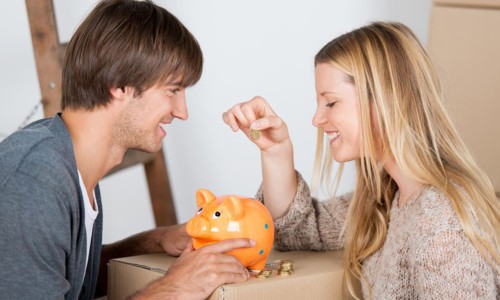 couple moving and thowing coins in a piggybank